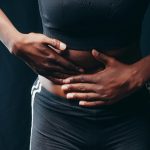 Donna che stringe l'addome per dolore e gonfiore addominale - Consulenza specialistica con il nutrizionista a Messina