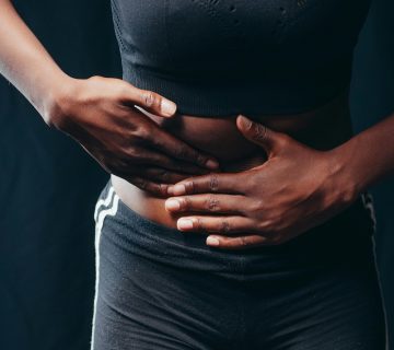 Donna che stringe l'addome per dolore e gonfiore addominale - Consulenza specialistica con il nutrizionista a Messina