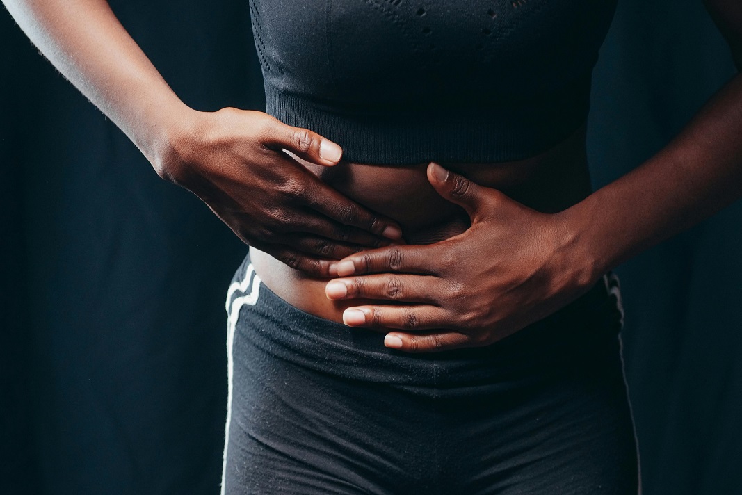 Donna che stringe l'addome per dolore e gonfiore addominale - Consulenza specialistica con il nutrizionista a Messina